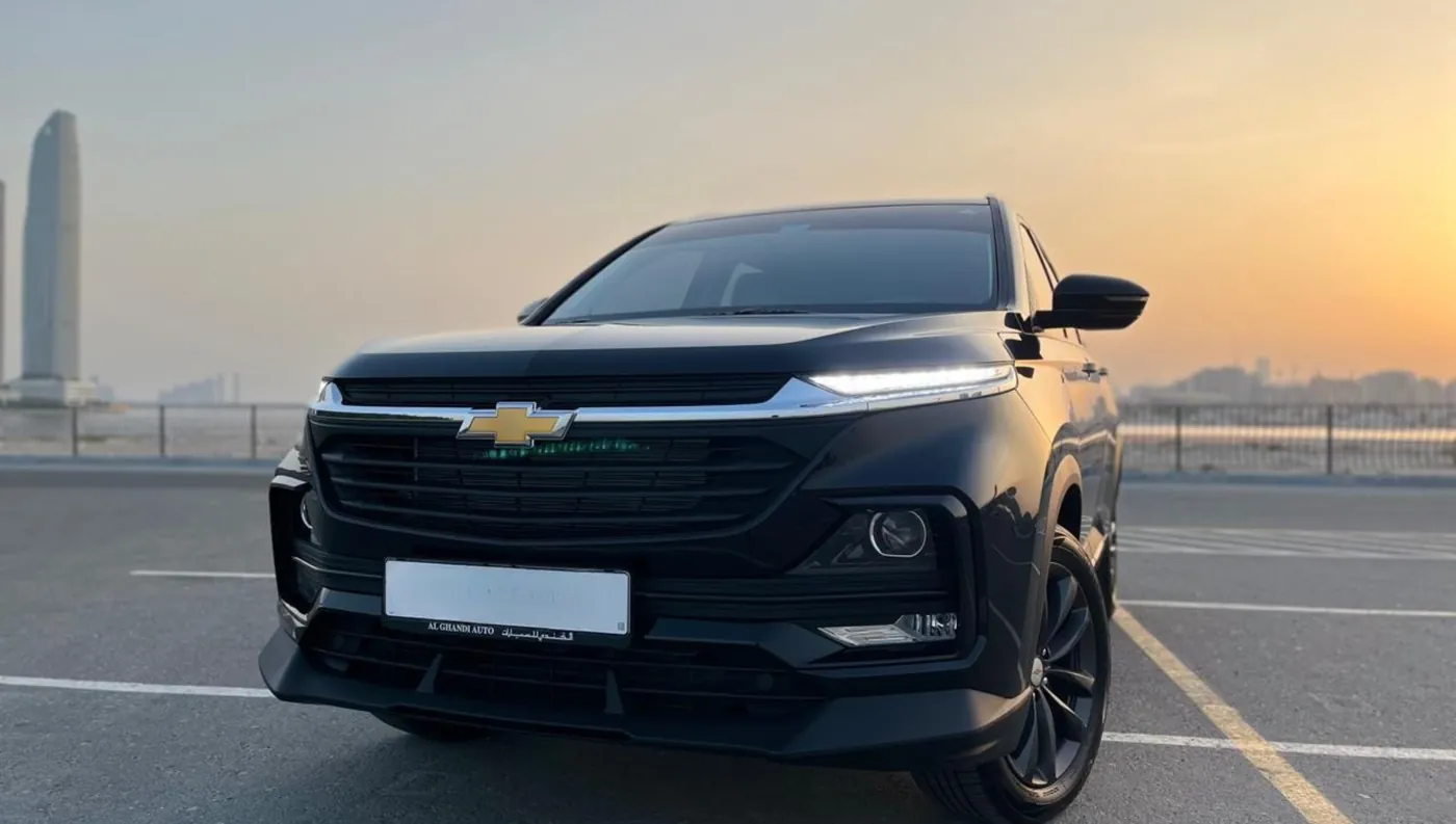 Black SUV parked with the Dubai skyline at sunset